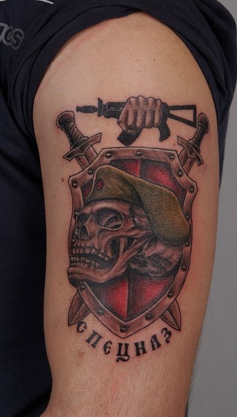 Татуировка на плече — череп на фоне цветного щита и меча с надписью «Спецназ»