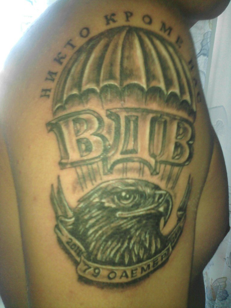 Татуировка на плече с изображением ястреба и парашюта с надписью «Никто кроме нас»