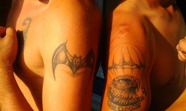 Две татуировки на плече. Одна с изображением летучей мыши, вторая с изображением орла и купола с ...